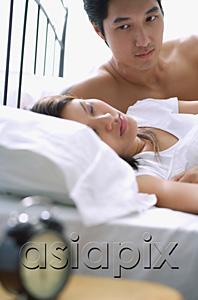 AsiaPix - Couple lying on bed, woman sleeping, man watching her