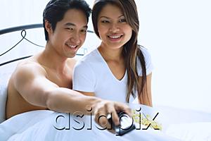 AsiaPix - Couple sitting on bed, watching TV