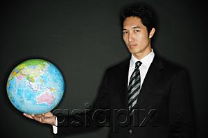 AsiaPix - Businessman holding globe in one hand, looking at camera