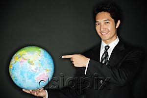 AsiaPix - Businessman holding globe in one hand, pointing to it with the other