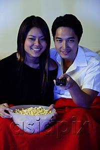 AsiaPix - Couple watching TV, woman holding bowl of popcorn, man holding remote control