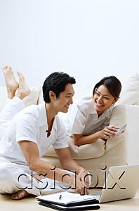 AsiaPix - Couple at home, looking at laptop, woman holding calculator
