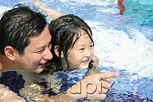 AsiaPix - Father and daughter in swimming pool, father pointing with finger
