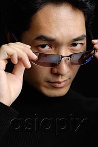 AsiaPix - Man adjusting sunglasses, looking at camera