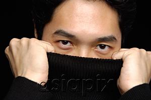 AsiaPix - Man pulling turtleneck over face, looking at camera