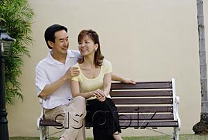 AsiaPix - Mature couple sitting on bench, man with arms around woman
