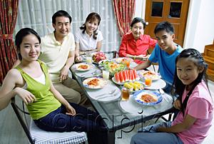 AsiaPix - Three generation family around dining table, smiling at camera