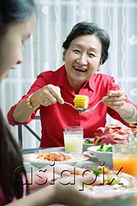 AsiaPix - Grandmother and granddaughter at dining table, eating