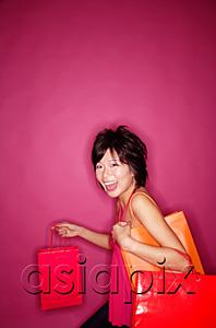AsiaPix - Young woman against pink background carrying shopping bags