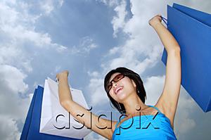 AsiaPix - Young woman with arms outstretched holding shopping bags, low angle view