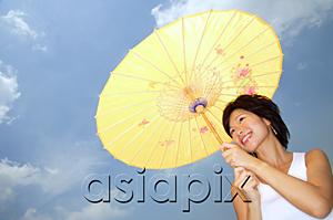 AsiaPix - Young woman with yellow umbrella, smiling, low angle view