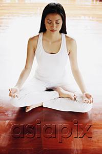 AsiaPix - Woman practicing yoga, sitting in lotus position, eyes closed