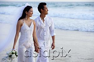 AsiaPix - Newlyweds walking on beach, holding hands, looking away