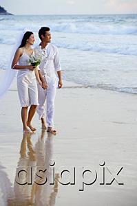 AsiaPix - Bride and groom walking on beach, looking out to sea