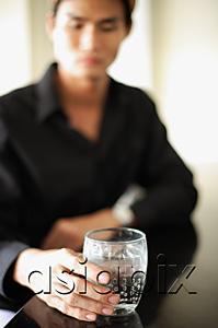 AsiaPix - Man sitting at counter, holding drink