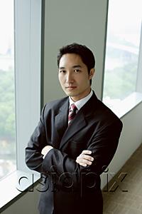 AsiaPix - Businessman standing next to window, arms crossed, looking at camera