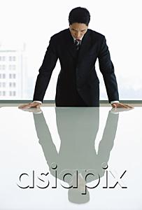 AsiaPix - Businessman standing with hands on table, looking down