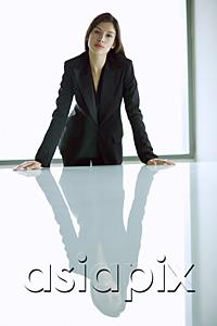 AsiaPix - Businesswoman standing with hands on table, looking at camera