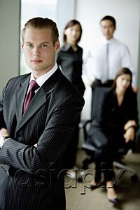 AsiaPix - Businessman standing with arms crossed, people in the background