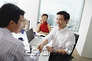 AsiaPix - Two businessmen exchanging business cards, woman looking at them