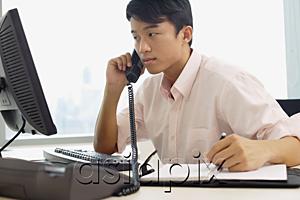 AsiaPix - Male executive sitting at office desk, using telephone