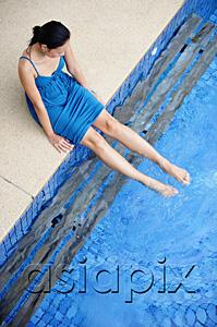 AsiaPix - Young woman sitting by swimming pool, dipping feet in water