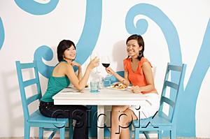 AsiaPix - Young women in cafe, toasting with wine glasses, smiling at camera