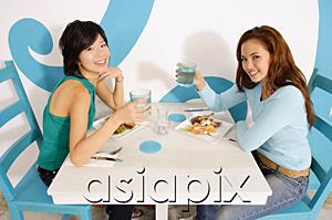 AsiaPix - Young women having lunch in cafe, raising water glasses to camera