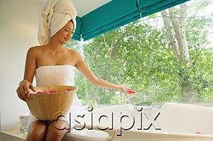 AsiaPix - Woman sitting at edge of bath tub, throwing flower petals into tub
