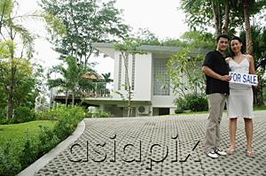 AsiaPix - Couple standing on driveway holding for sale sign