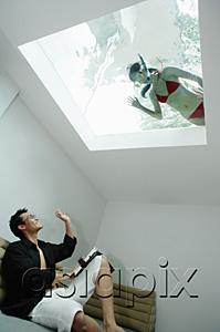 AsiaPix - Man in living room, waving at woman in swimming pool through the skylight
