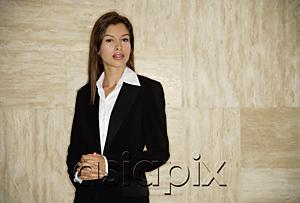 AsiaPix - Businesswoman standing, hands clasped, looking at camera