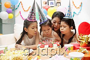 AsiaPix - Mother with three girls celebrating a birthday, blowing candles on cake