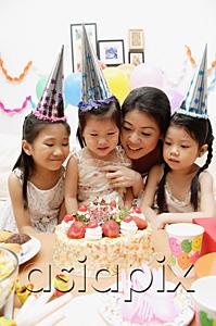 AsiaPix - Mother with three daughters celebrating a birthday, looking at cake