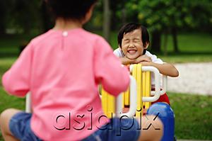 AsiaPix - Two girls on a seesaw, one leaning on arms, smiling, eyes closed