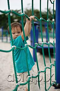 AsiaPix - Young boy in playground, holding on to net