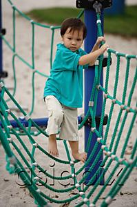 AsiaPix - Young boy in playground, walking on net bridge