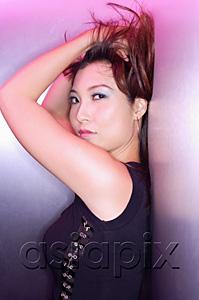AsiaPix - Woman leaning on wall, looking at camera, hands on head