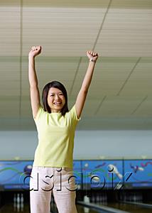 AsiaPix - Woman standing at bowling alley, hands in the air