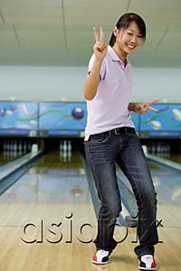AsiaPix - Woman at bowling alley, smiling, making peace sign