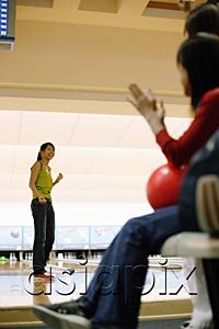 AsiaPix - Woman at bowling alley, turning to look at friends behind her
