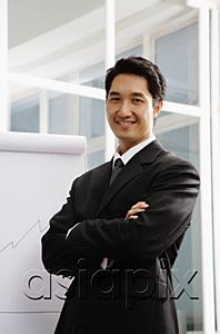 AsiaPix - Businessman standing next to flipchart, smiling
