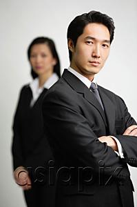 AsiaPix - Businessman with arms crossed, woman in the  background