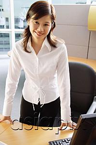 AsiaPix - Businesswoman standing in cubicle, smiling at camera