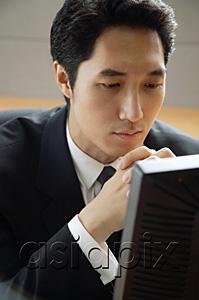 AsiaPix - Businessman sitting at desk, looking at computer monitor