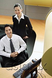 AsiaPix - Businessman and woman in office cubicle, smiling at camera