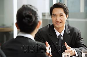 AsiaPix - Businessman having discussion with businesswoman, over the shoulder view
