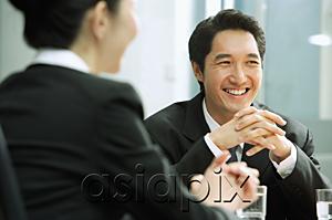 AsiaPix - Businessman smiling, hands clasped, woman in the foreground