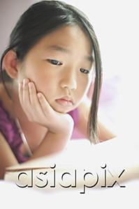 AsiaPix - Girl with hand on chin, looking at book