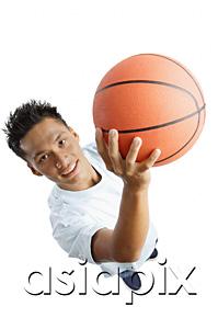 AsiaPix - Young man holding basketball, looking up at camera